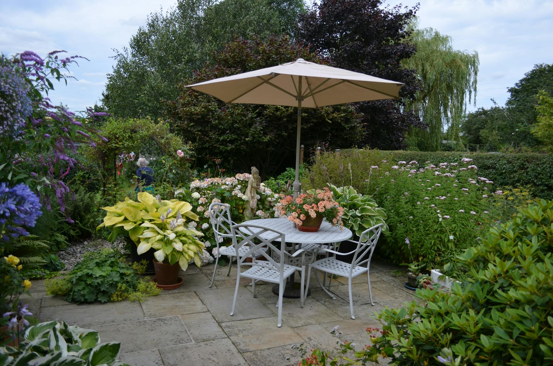 Tuinterras met tafel, stoelen, parasol en bloeiende borders